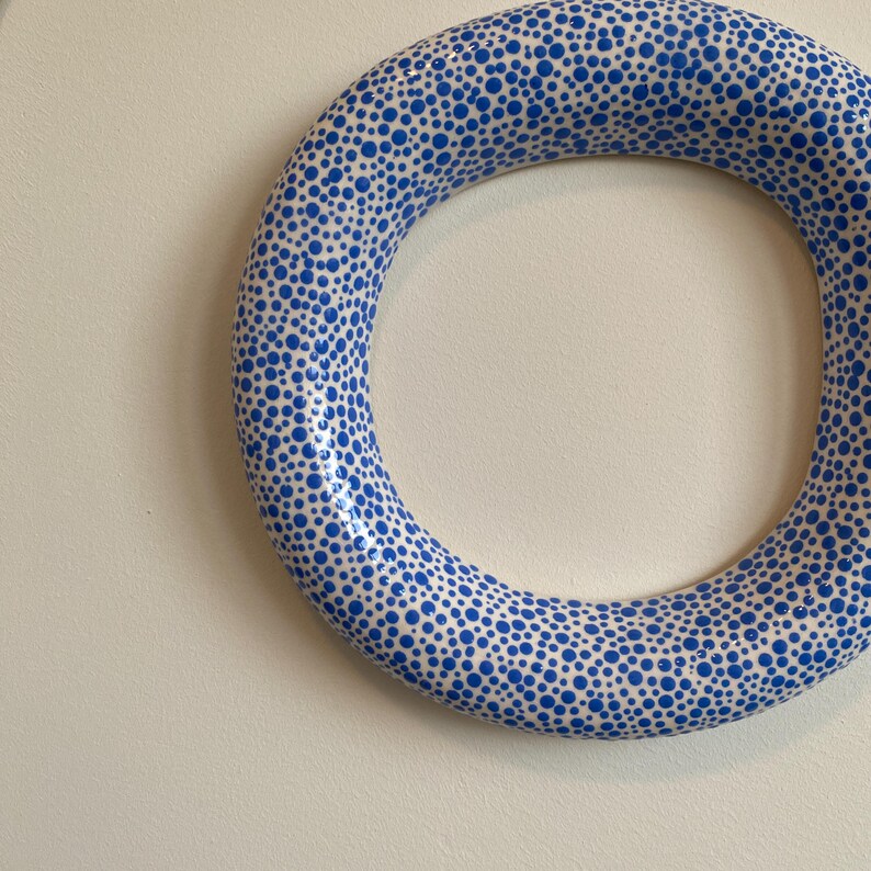 Puede incluir: Un anillo de cer&aacute;mica blanca con un patr&oacute;n de lunares azules. El anillo es grueso y tiene una gran abertura en el centro.