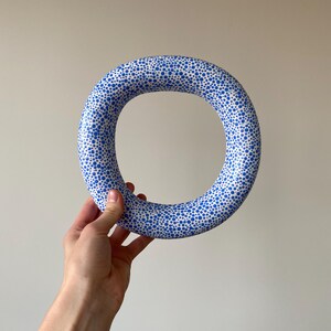 Puede incluir: Un anillo de cer&aacute;mica blanca con un patr&oacute;n de lunares azules. El anillo es grueso y tiene una gran abertura.