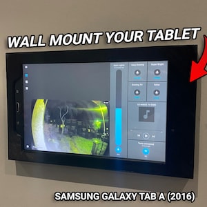 May include: A black wall mount holding a Samsung Galaxy Tab A (2016) tablet. The tablet displays a control panel with various buttons and a live camera feed. Text on the mount reads "WALL MOUNT YOUR TABLET."