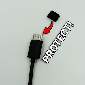 Pode incluir: Um cabo HDMI preto com uma tampa protetora preta. A tampa foi removida e o texto "PROTECT!" está escrito na imagem.