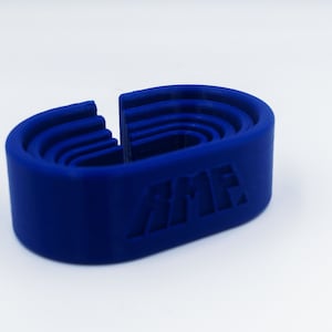 May include: A vibrant blue, 3D-printed object with a unique, layered design. The object has a curved, oval shape with a central opening. The letters "AMF" are embossed on the side. The object is likely a tool or a component.