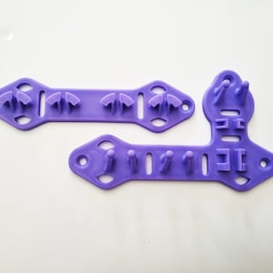 Pode incluir: Duas ferramentas de pl&aacute;stico roxo com v&aacute;rios orif&iacute;cios e sali&ecirc;ncias. As ferramentas s&atilde;o projetadas para artesanato e t&ecirc;m uma variedade de formas e tamanhos.