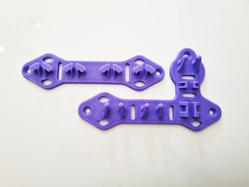 Pode incluir: Duas ferramentas de pl&aacute;stico roxo com v&aacute;rios orif&iacute;cios e sali&ecirc;ncias. As ferramentas s&atilde;o projetadas para artesanato e t&ecirc;m uma variedade de formas e tamanhos.