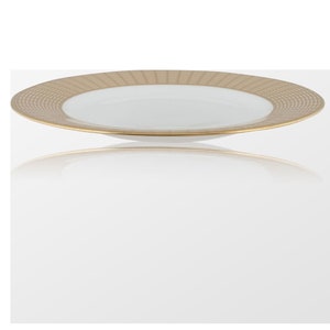 Puede incluir: Un plato de cena de cerámica blanca con un borde dorado y un patrón geométrico sutil.