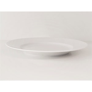 May include: A white ceramic dinner plate with a slightly raised rim.