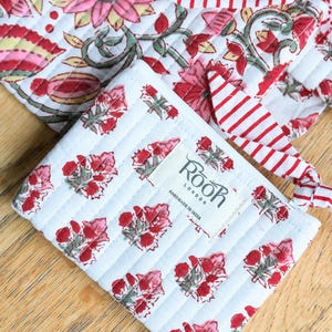 May include: White quilted fabric items with red floral patterns and red and white striped accents. One item is a small square with a label that reads "Roor London Handmade in India". The other item is a larger square with a similar floral pattern.