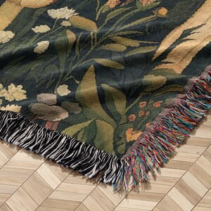 May include: A woven tapestry throw blanket with a floral pattern in shades of green, brown, and yellow. The blanket has a fringe border with black and multi-colored threads.