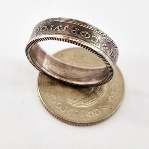 May include: A silver coin ring with the words "1 JPY" and "昭和 63 年" engraved around the band. The ring is sitting on top of a silver coin with the words "日本国" and "500 円" engraved on it.