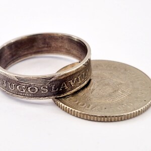 May include: A silver ring made from a Yugoslavian coin. The ring is made from the outer edge of the coin, with the inscription "JUGOSLAVIJA" visible. The coin is lying next to the ring.