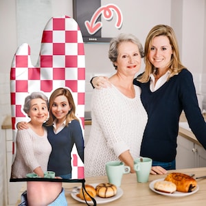 Könnte beinhalten: Ein rot-weiß karierter Ofenhandschuh mit einem Foto von zwei Frauen. Der Handschuh wird von einer Person hochgehalten. Der Hintergrund zeigt zwei Frauen, Tassen und Gebäck auf einer Holzoberfläche.