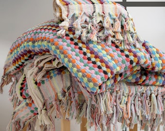 May include: A stack of colorful Turkish towels with fringe. The towels are made of cotton and have a variety of patterns, including polka dots, stripes, and geometric designs.
