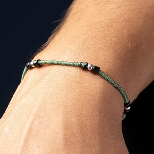 Op de afbeelding: Een groene en zwarte kralen armband met zilveren accenten.