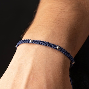 Op de afbeelding: Een gevlochten armband in marineblauw met zilveren kralen.