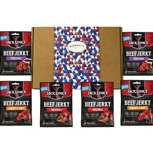 May include: A brown cardboard box with a blue, red and white geometric pattern on the top. The box contains six individual packets of Jack Link's beef jerky in the flavours Teriyaki, Sweet & Hot, and Original.
