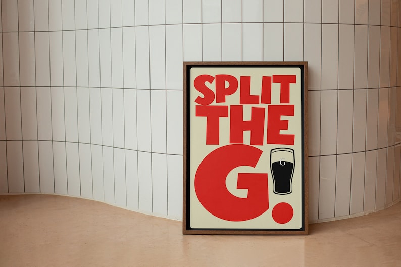 K&ouml;nnte beinhalten: Ein gerahmtes Poster mit dem Text "SPLIT THE G!" in roten Buchstaben. Neben dem "G" befindet sich eine schwarze Silhouette eines Bierglases.