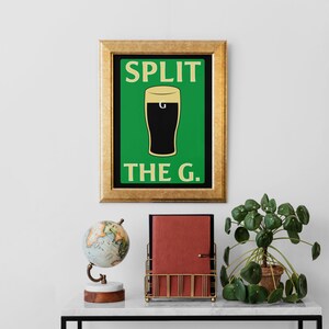 K&ouml;nnte beinhalten: Ein gerahmter Druck mit gr&uuml;nem Hintergrund und einer schwarzen Silhouette eines Bierglases mit dem Text "SPLIT THE G." in Gelb.