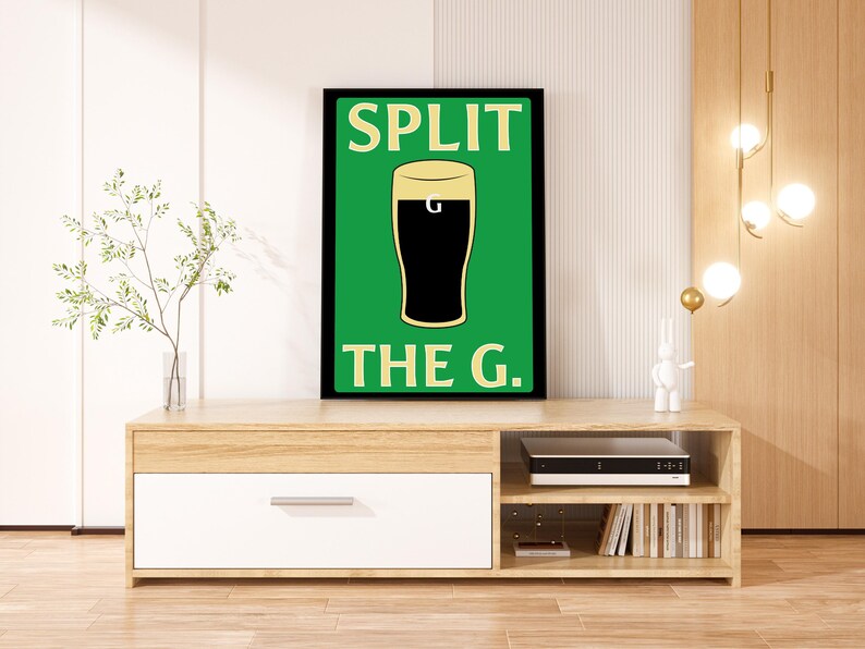 K&ouml;nnte beinhalten: Ein schwarzer gerahmter Druck mit gr&uuml;nem Hintergrund und wei&szlig;em Rahmen. Der Druck zeigt ein Glas dunkles Bier mit dem Text "SPLIT THE G." in Wei&szlig;.