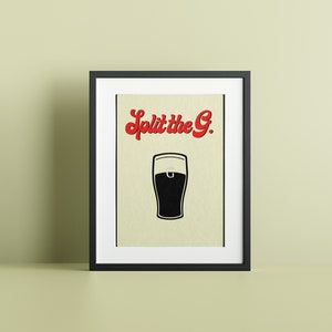 May include: Framed art print featuring a black and white illustration of a pint of beer. The text "Split the G." is in red, stylized lettering above the beer glass. The print is in a black frame.