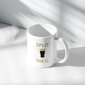 May include: White ceramic mug with a black and gold graphic of a pint glass and the text "SPLIT THE G."