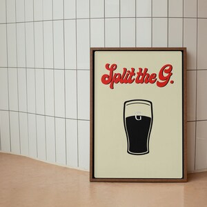 May include: A framed print with a cream background features a black and white illustration of a pint of beer. The text "Split the G." is in red, stylized lettering above the pint. The frame is a dark brown color.