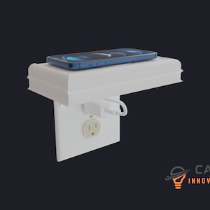 May include: A white wall mounted shelf with a built-in wireless charging pad for a smartphone. The shelf is attached to a standard electrical outlet. The phone is charging on the pad.