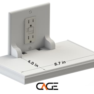 May include: White wall-mounted shelf with an electrical outlet attached. The shelf measures 8.7 inches wide and 4 inches deep.