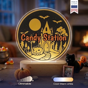 May include: A circular acrylic light sign with a wooden base featuring a Halloween scene with a haunted house, a pumpkin, bats, and a full moon. The text Candy Station is printed in the center. The sign includes dimmable and color settings.