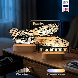 May include: Two personalized car-themed night lights with wooden bases. One features a checkered flag and a car, the other displays two cars with flames and the name "Brandon". The third light has a car with the name "Daniel". The lights are dimmable and offer cool-warm white light.