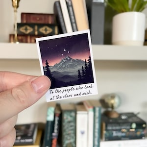 Op de afbeelding: Een witte fotokaart met een paarse bergketen en een sterrenhemel. De tekst op de kaart luidt "Voor de mensen die naar de sterren kijken en wensen."