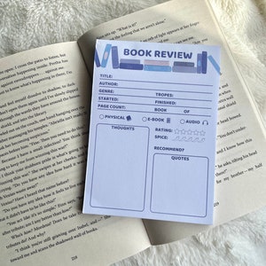 Op de afbeelding: Een blauwe en witte boekrecensietemplate met secties voor titel, auteur, genre, start, pagina aantal, tropes, afgerond, boek, fysieke gedachten, e-boek, audio, beoordeling, kruiden, aanbevelen en citaten. De template is ontworpen om lezers te helpen hun gedachten en gevoelens over een boek te ordenen.