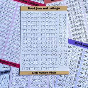 Può includere: Un assortimento di fogli adesivi colorati per il book journaling, con disegni di stelle, fantasmi, fiamme e cuori. Ogni foglio riporta le scritte "Book journal ratings" e "Little Modern Witch".