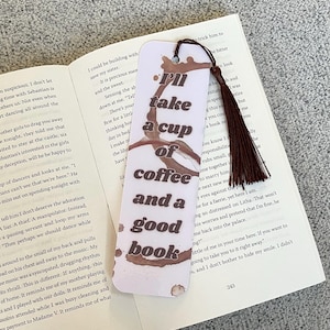 Op de afbeelding: Een witte bladwijzer met een bruine koffie vlek en de tekst "I'll take a cup of coffee and a good book".