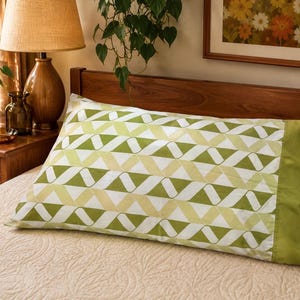 May include: A rectangular pillowcase featuring a geometric pattern of interlocking triangles in shades of olive green, lime green, and white. The pillowcase has a solid olive green border on the right side and a smooth, soft fabric texture.
