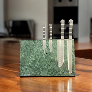 May include: A green marble knife block with four stainless steel knives. The knives have striped handles and various blade shapes. The block is on a wooden countertop in a kitchen setting.