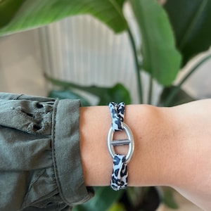 Può includere: Un braccialetto elastico con stampa animalier bianco e nero con chiusura in metallo argentato.