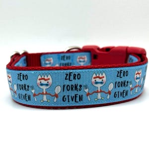 May include: A blue and red dog collar with a repeating pattern of a cartoon character holding a fork and spoon with the text "Zero Forks Given".