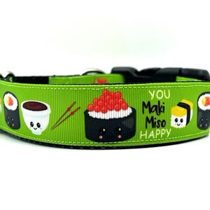 May include: Green dog collar with a sushi theme. It features a variety of sushi rolls, soy sauce, chopsticks, and the text "You Maki Miso Happy".