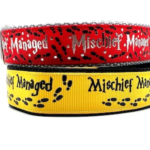 Peut inclure: Deux colliers pour chien, l'un noir et jaune et l'autre rouge et gris. Les deux colliers présentent le texte "Mischief Managed" et un motif de traces de pas.