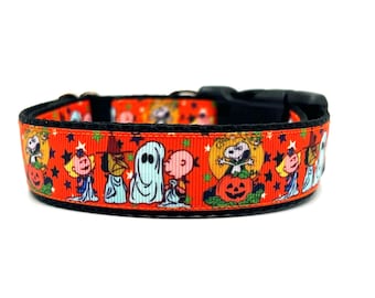May include: Orange and black dog collar with a Halloween-themed print featuring the Peanuts characters dressed in costumes. The print includes a ghost, a witch, a pumpkin, and other characters.