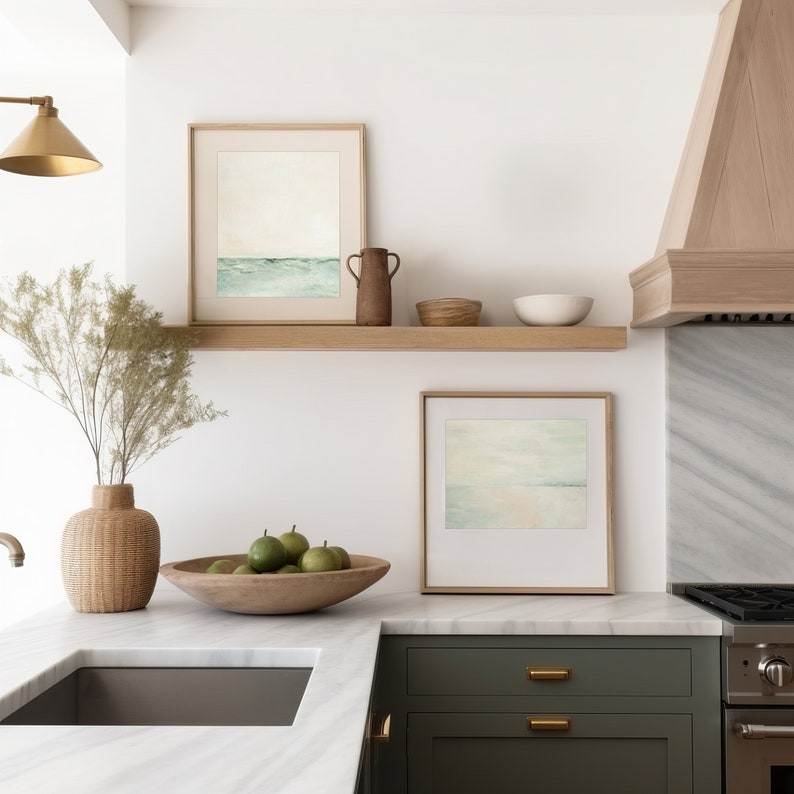 Minimalist horizontal beach landscape print hangs in a neutral coastal kitchen.