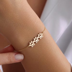 May include: Gold bracelet with paw print charms engraved with the names Josie, Jennie, and Brutus.