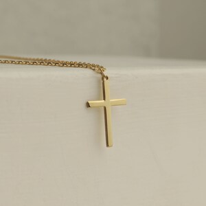 Puede incluir: Un collar de cadena de oro con un simple colgante de cruz de oro.