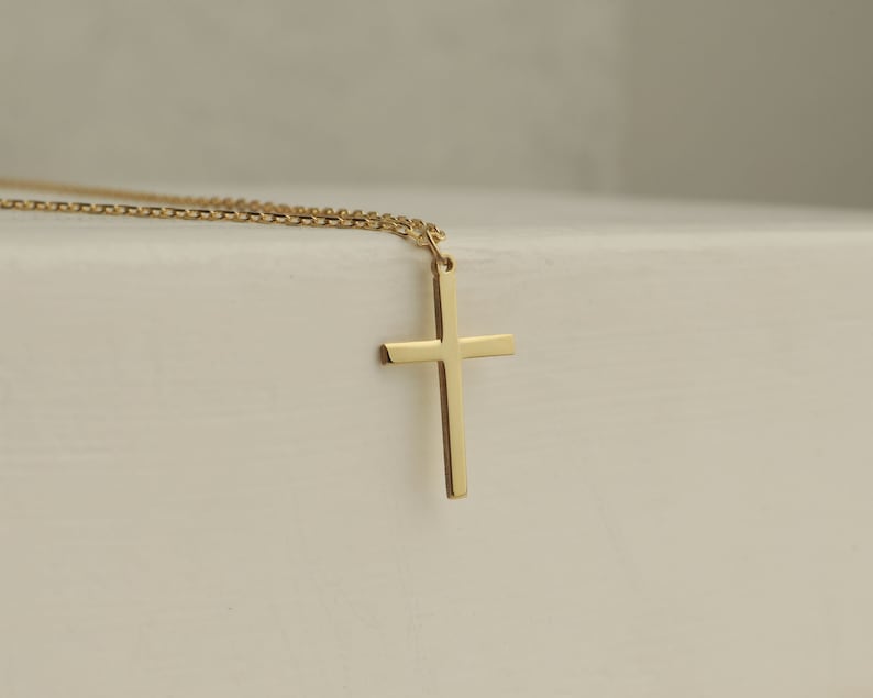 Puede incluir: Un collar de cadena de oro con un simple colgante de cruz de oro.