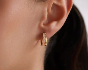 May include: Gold hoop earrings with a row of small clear stones around the edge.