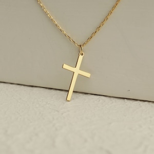 Puede incluir: Un collar de cadena de oro con un simple colgante de cruz de oro.