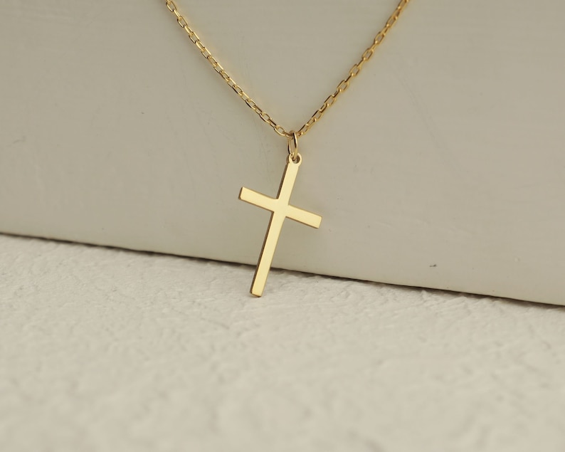 Puede incluir: Un collar de cadena de oro con un simple colgante de cruz de oro.