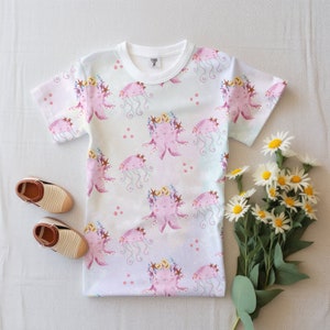 May include: A white t-shirt with a pink octopus and jellyfish pattern. The octopus is wearing a flower crown and the jellyfish has a pink bell. The shirt has a light pink, blue, and yellow ombre effect.