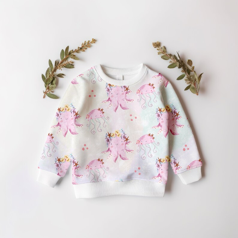May include: White sweatshirt with a pink and purple octopus print. The octopus is wearing a flower crown. The background is a light blue and white watercolor pattern.