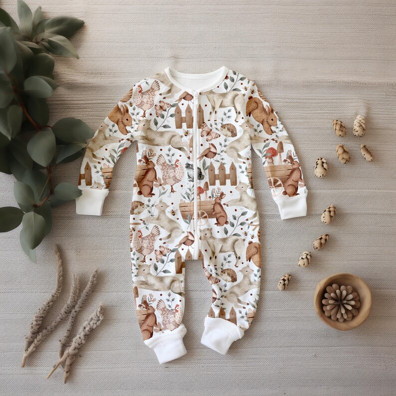 May include: White baby onesie with a zipper closure and a woodland animal print. The print features squirrels, rabbits, birds, and mushrooms in brown and beige tones.
