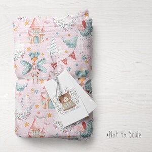 May include: Pink fabric with a repeating pattern of fairies, castles, stars, and flowers. The fabric is folded and tied with a string. A white tag with the text "CLAIRE EDDIE ART" is attached to the fabric.